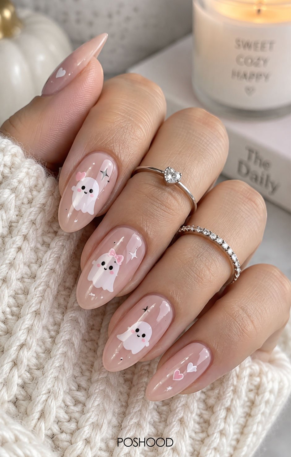Glossy nude pink almond nails decorated with cute white ghosts, pink hearts, pastel accents, and sparkle details.
