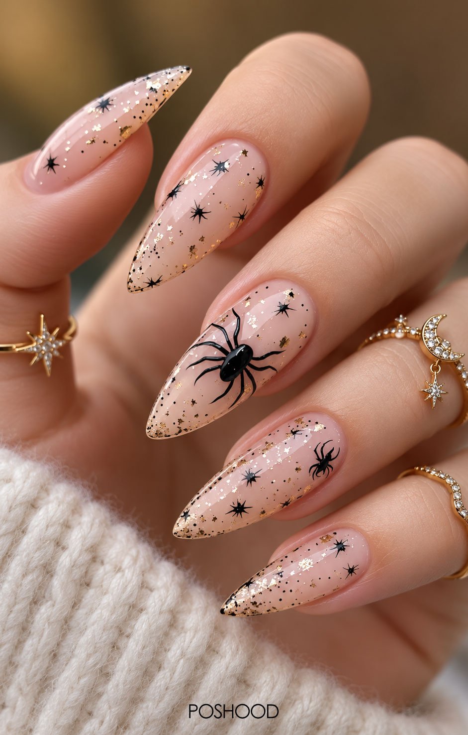 Glossy blush pink almond-shaped nails with black spider web designs, rhinestones, and silver glitter accents.