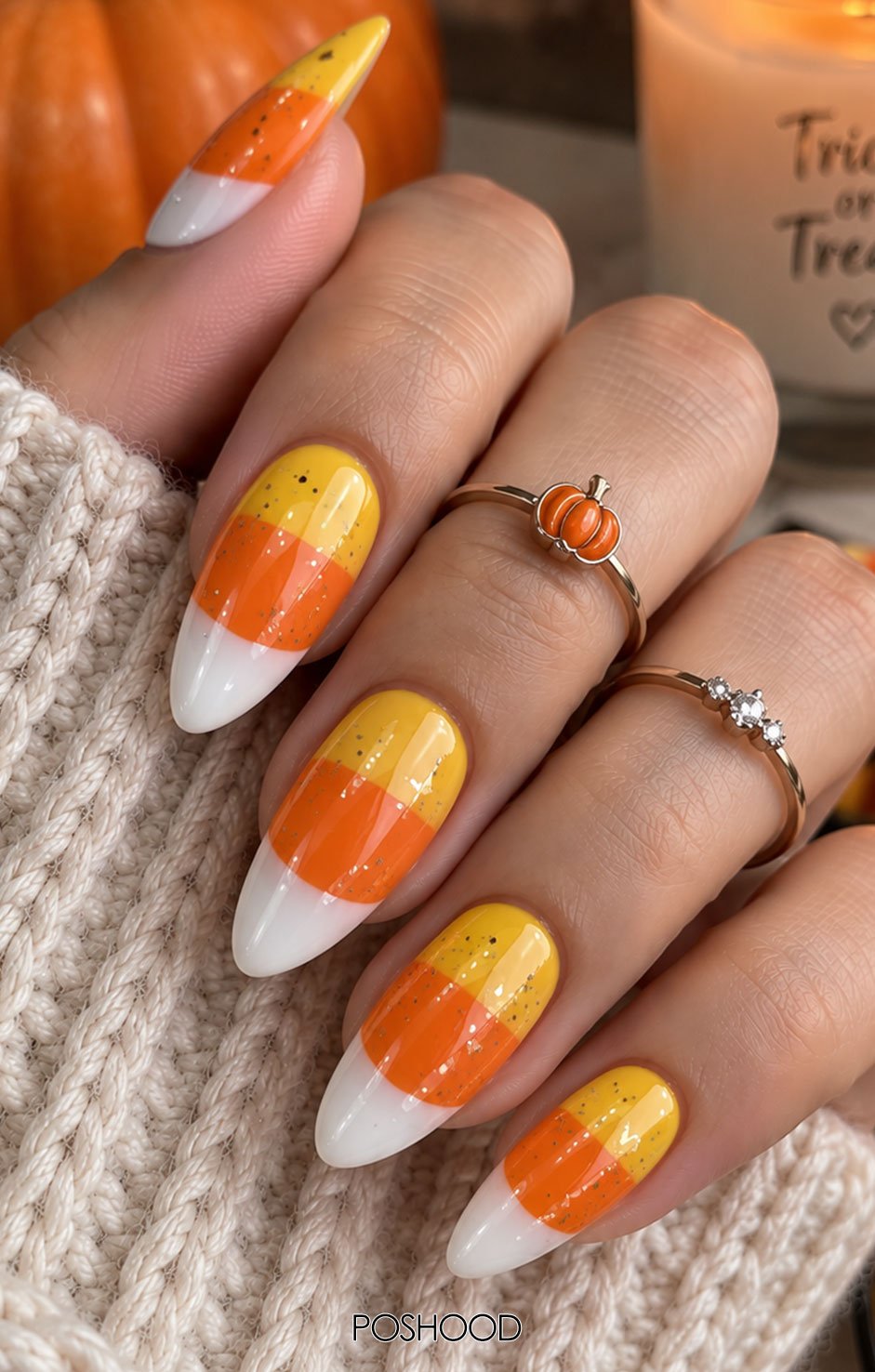Glossy almond-shaped candy corn Halloween nails with yellow, orange, and white color blocking and glitter accents.