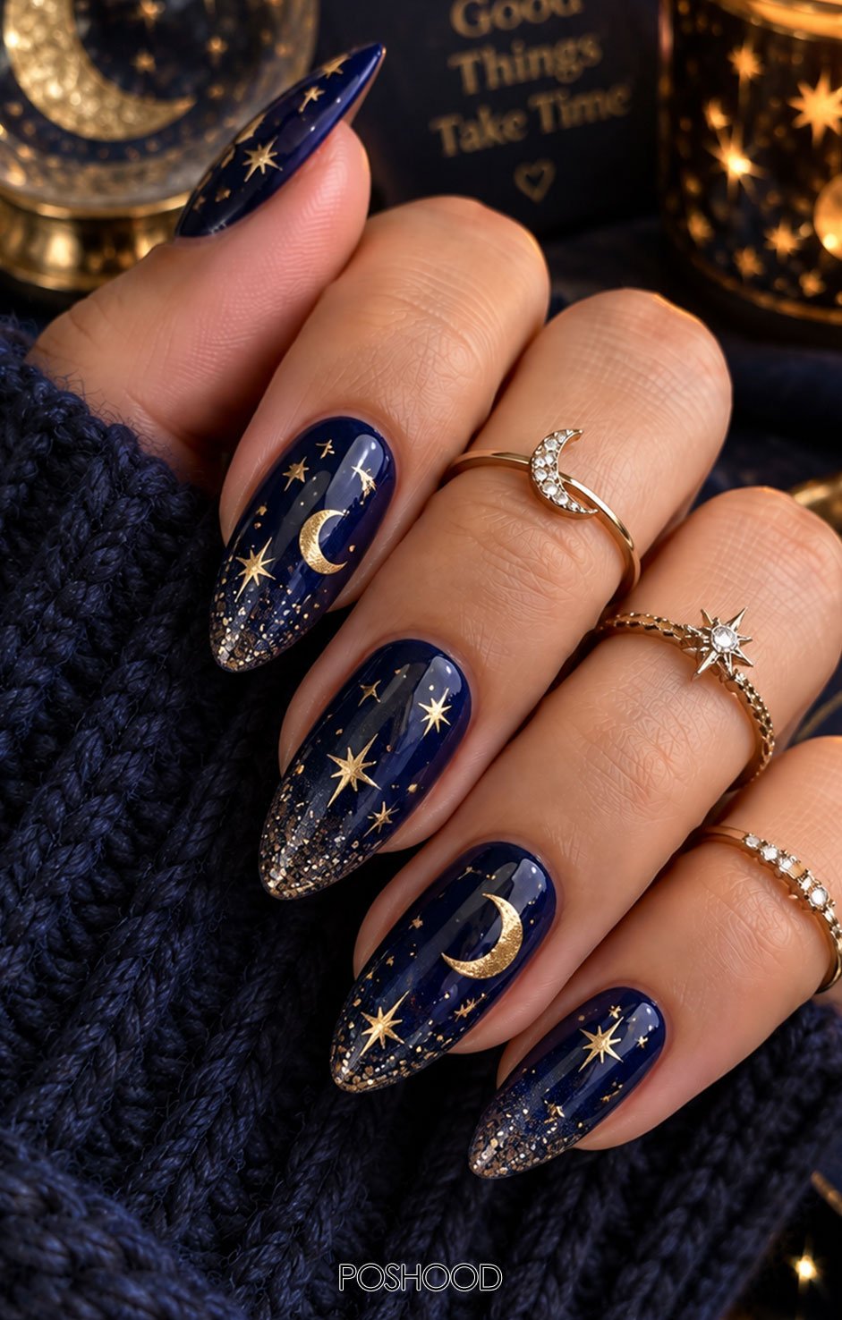 Glossy deep navy almond-shaped nails decorated with golden moons, sparkling stars, and shimmer accents.