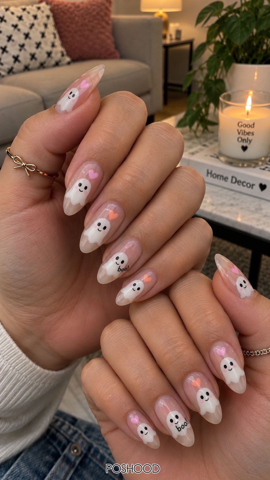 Cute Halloween nails ideas featuring smiling white ghost nail art with pink and orange hearts on sheer pink almond nails.