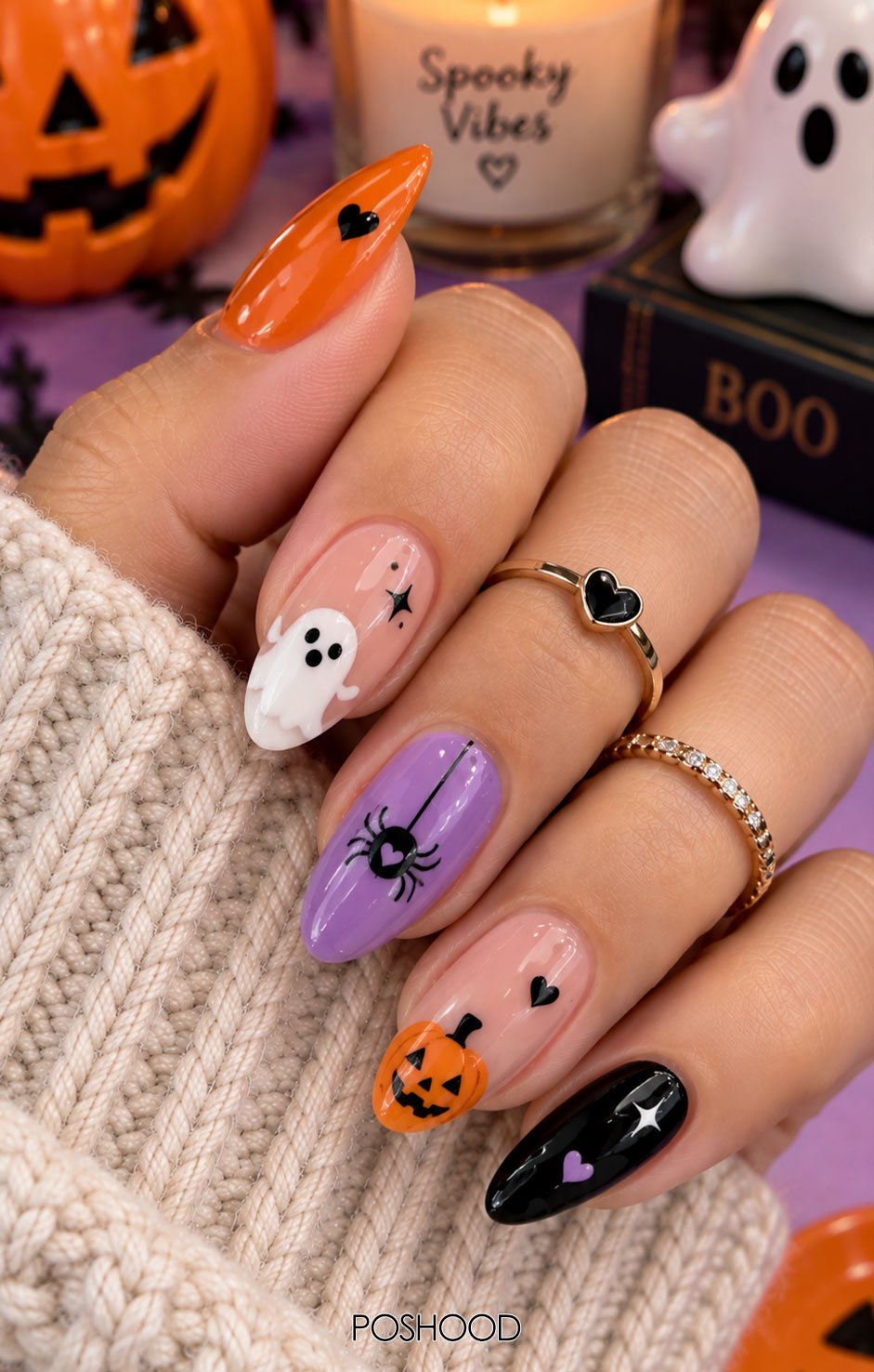 Glossy almond-shaped Halloween nails featuring orange, purple, black, and white candy-inspired swirl patterns with cute Halloween accents and gold rings.