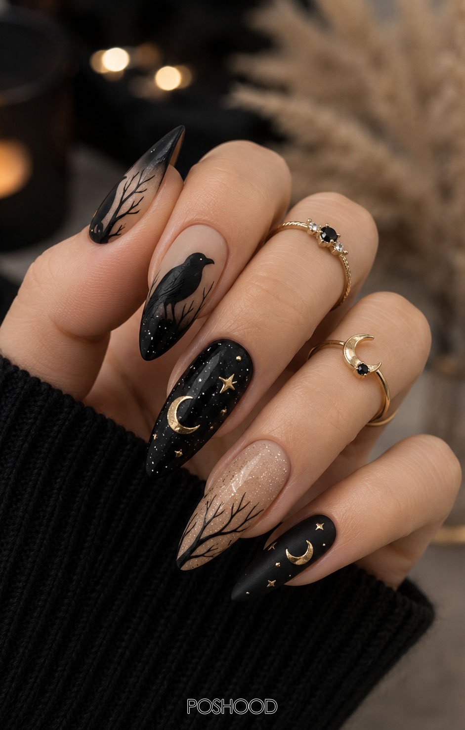 Glossy midnight blue almond-shaped nails featuring golden moon phases, tiny stars, and shimmering galaxy accents, styled with celestial gold rings against a cozy, natural background.