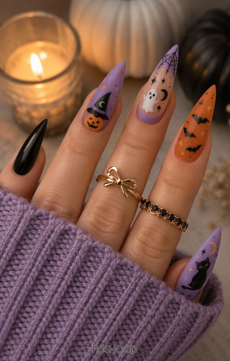 Long almond-shaped Halloween nails featuring lavender, orange, and black designs with witch hats, pumpkins, ghosts, bats, stars, and black cats, styled with a cozy purple knit sleeve and gold rings.