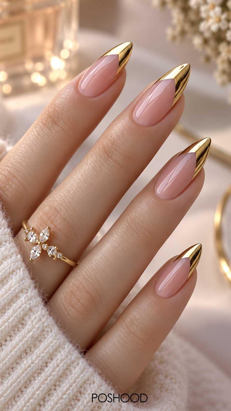 Blush pink almond nails with shiny metallic gold French tips and a delicate floral ring